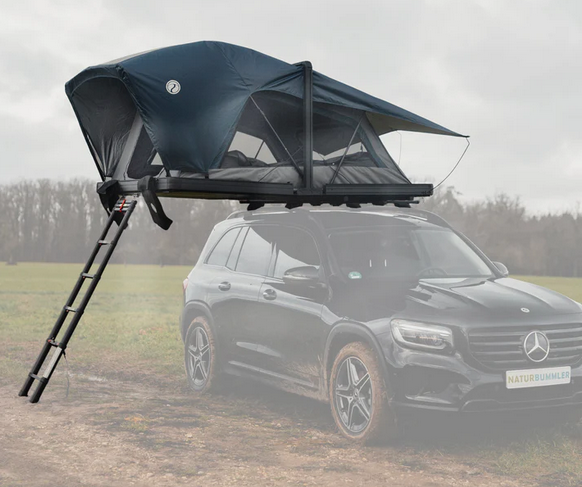 Ein schwarzer Mercedes SUV steht auf einer Wiese mit einem Dachzelt und Leiter